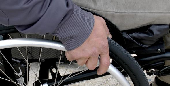 A man's hand on the wheel of a wheelchair